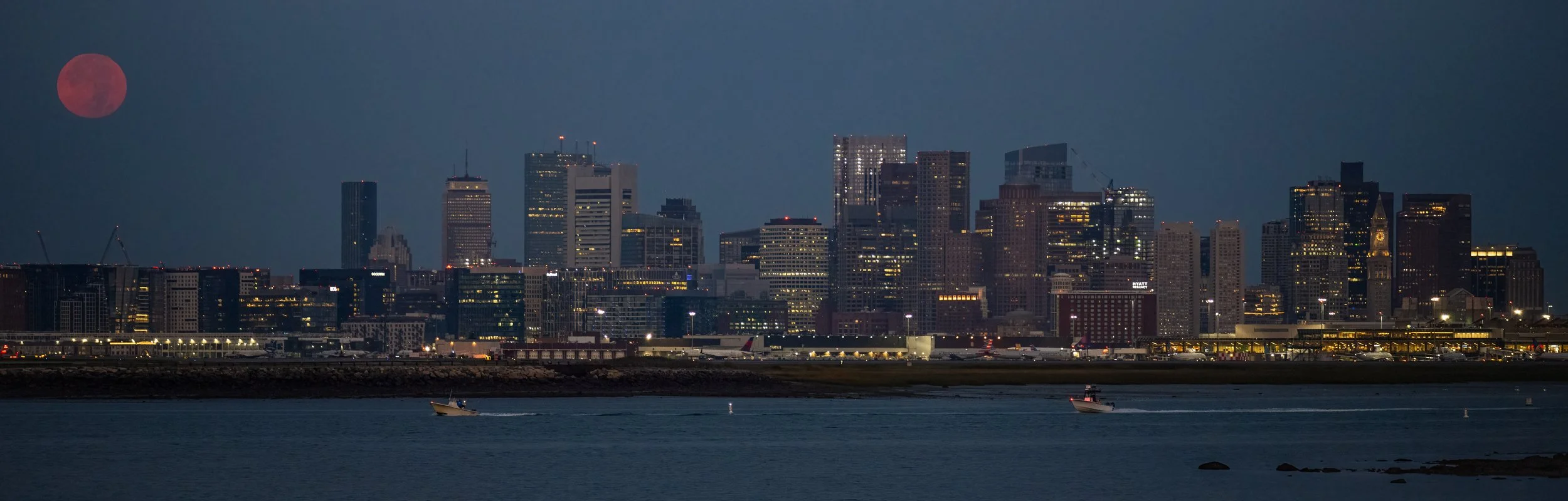 Full Harvest Moon sets behind the Boston Skyline