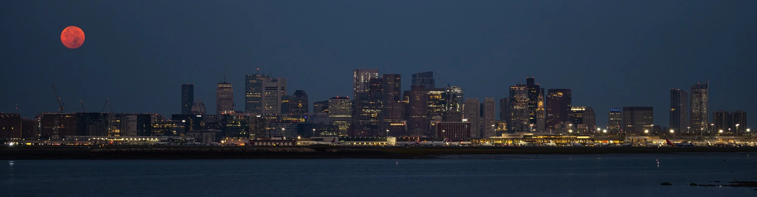 Full Harvest Moon sets behind the Boston Skyline