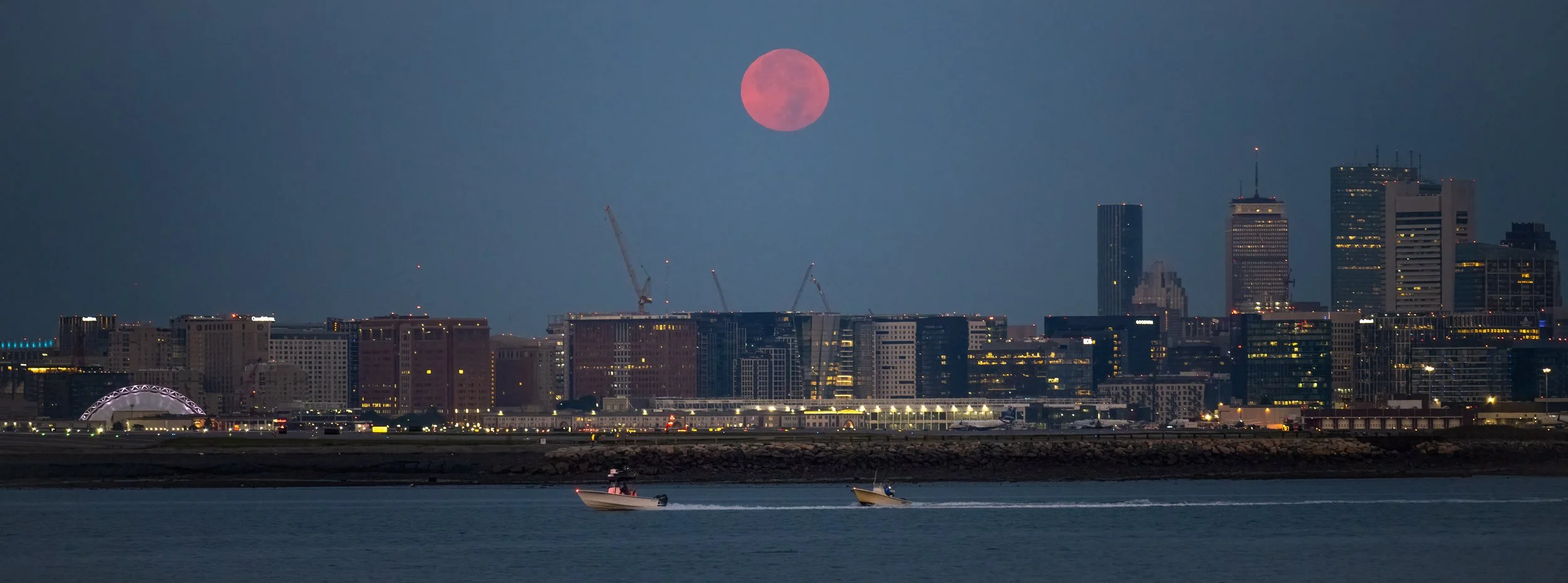 Full Harvest Moon sets behind the Boston Skyline